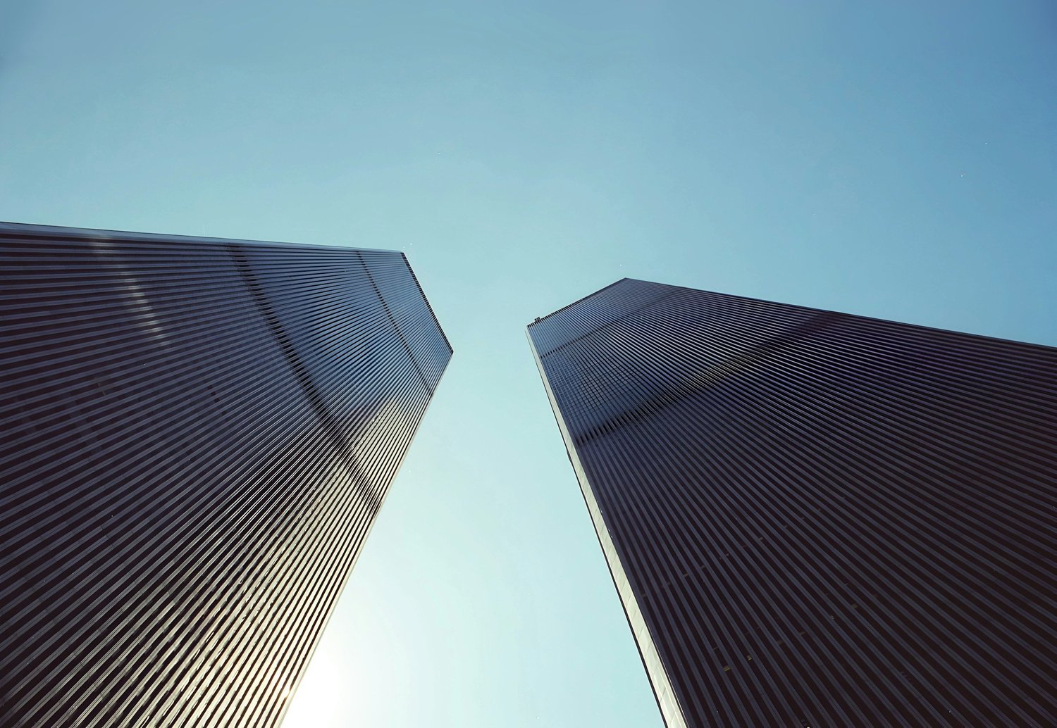 Two tall skyscrapers seen from below against a clear blue sky