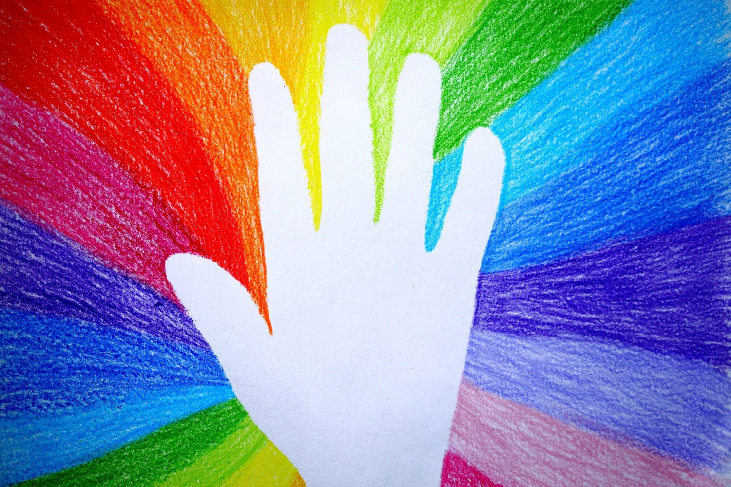 White paper cutout of a hand on a background of colored pencil rainbow stripes