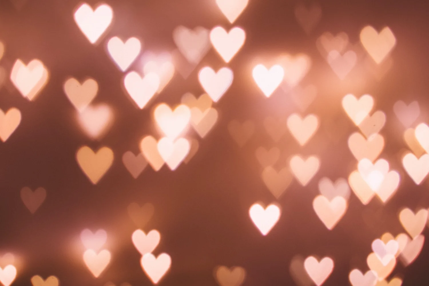 Blurred pink and peach heart-shaped lights on a dark background