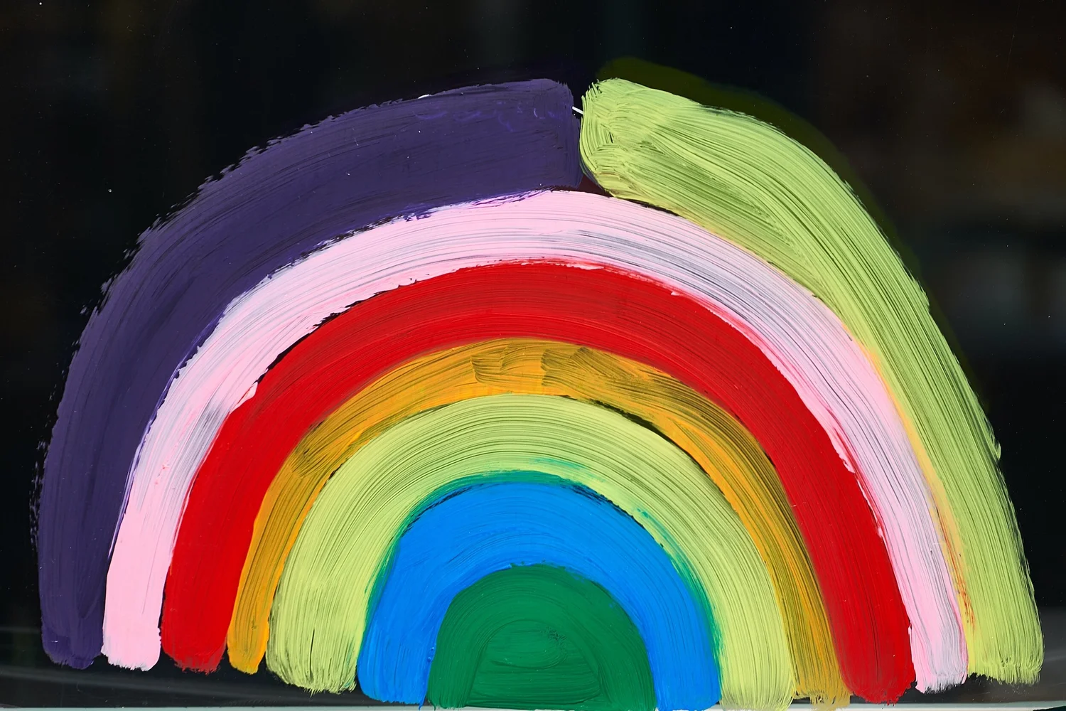 Hand-painted rainbow in thick brushstrokes against a dark background