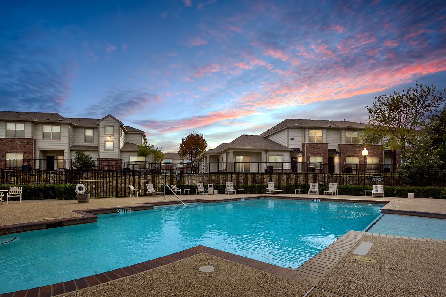 Pool deck with seating and large swimming pool at evening time