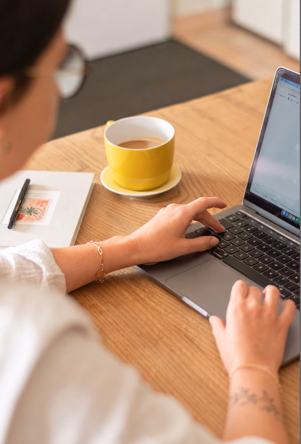 Person working on a laptop beside a cup of coffee