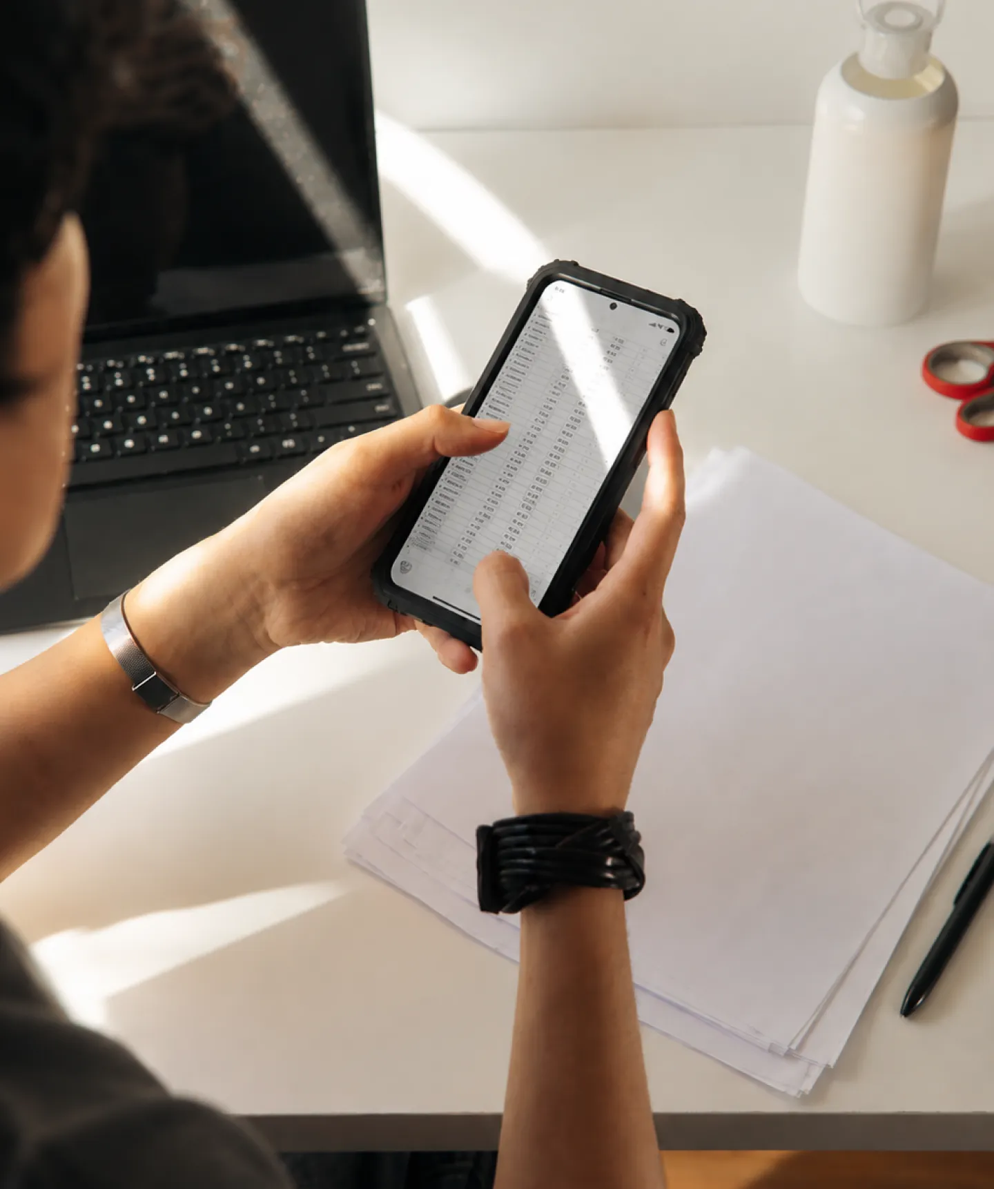 A person reviewing claim data on a phone at a desk