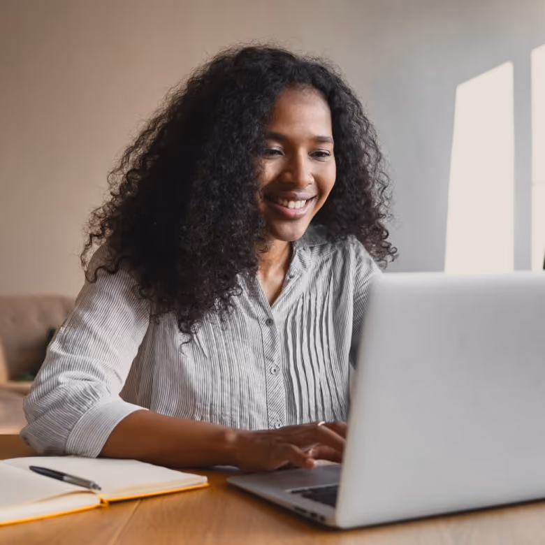 Team member smiling while working on a laptop