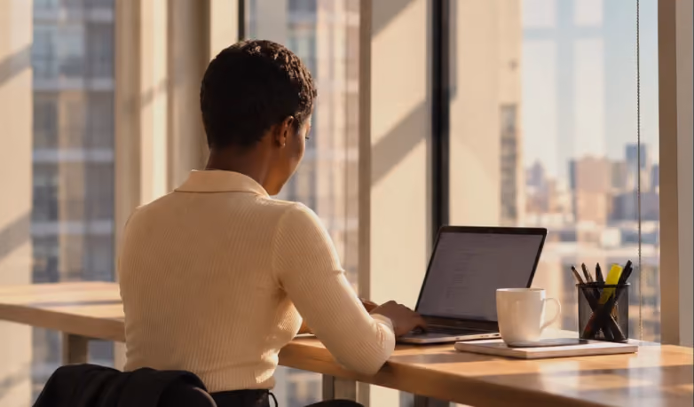 Person working on a laptop by a sunlit office window