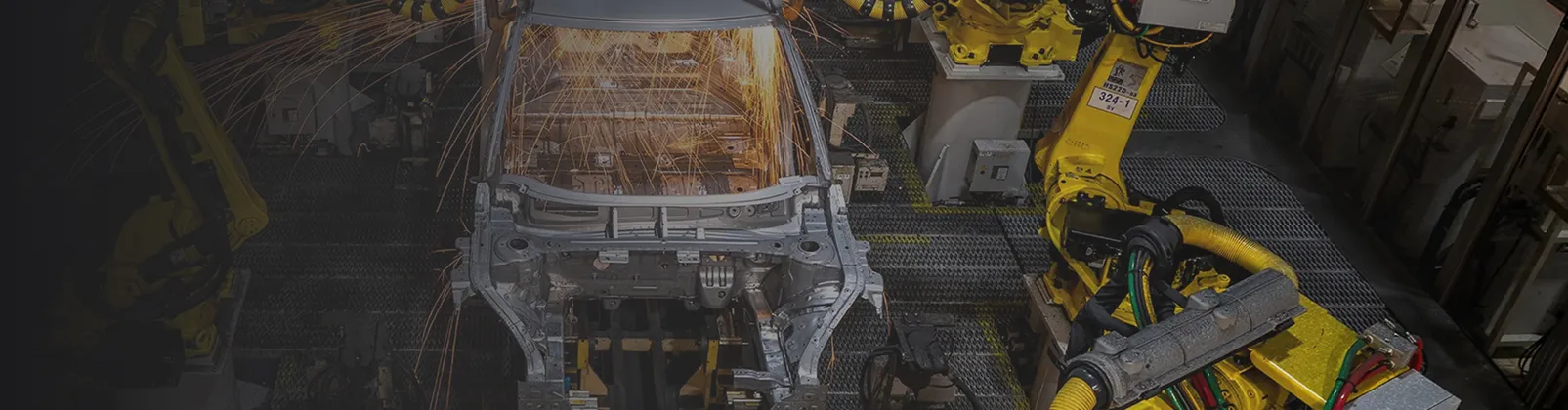 Robots weld car frame in an industrial automotive manufacturing plant.