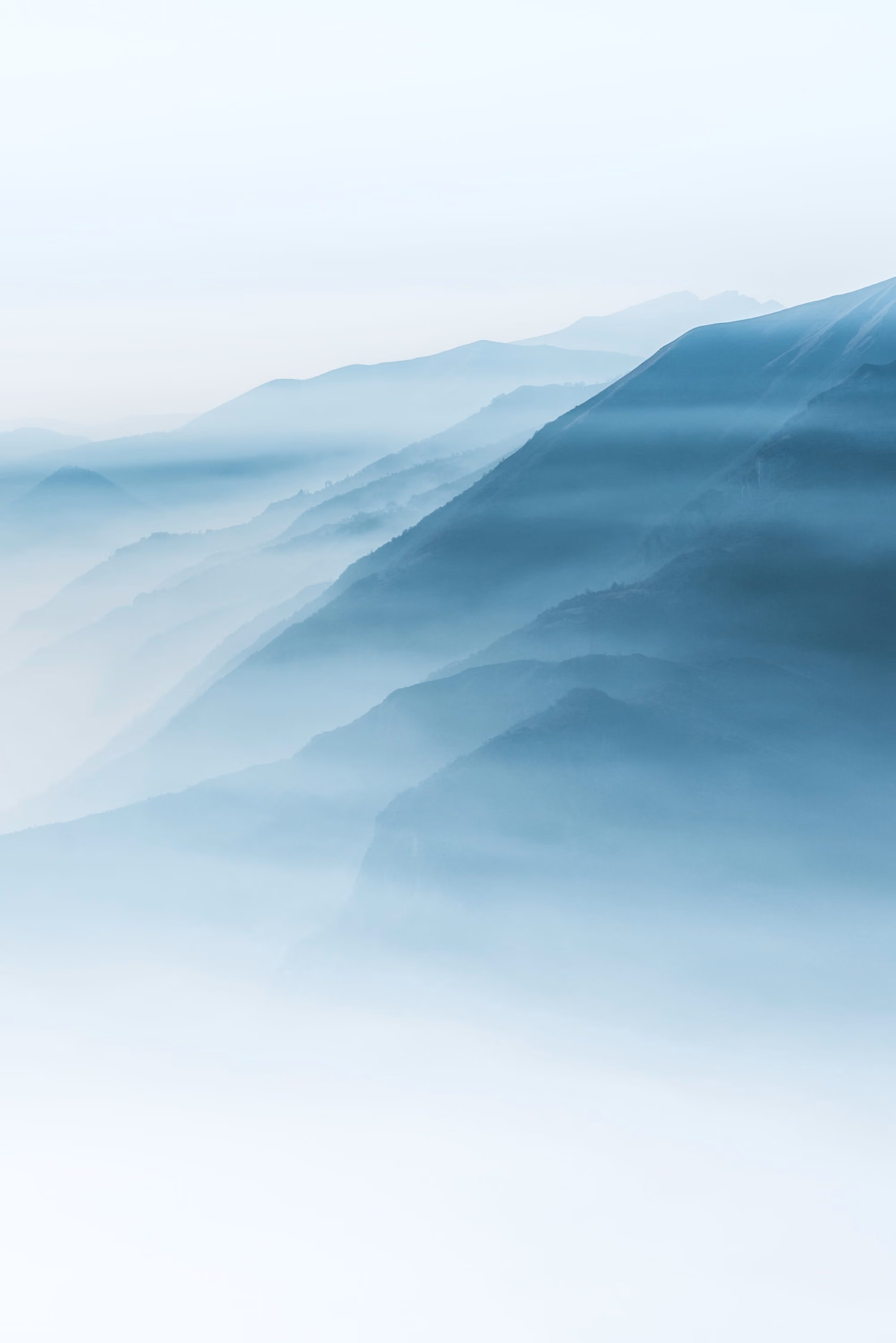 Nebelverhangene blaue Bergketten, die sich sanft in der Ferne abzeichnen.