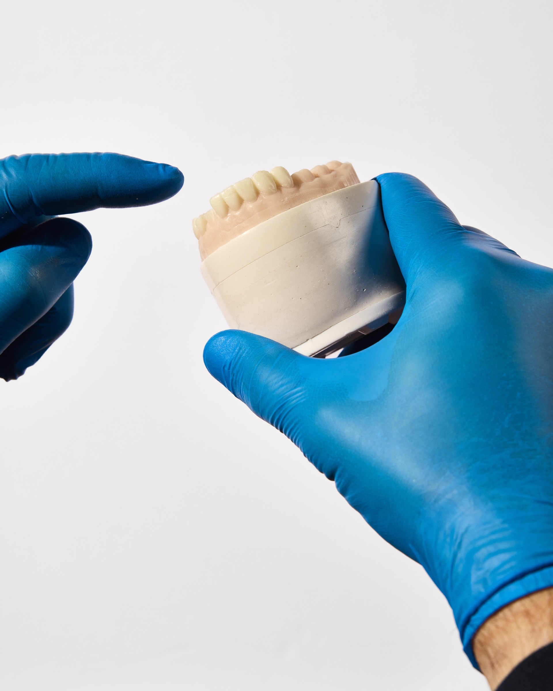 Toothbrush, toothpaste tube, and dental floss container on beige tiled surface.