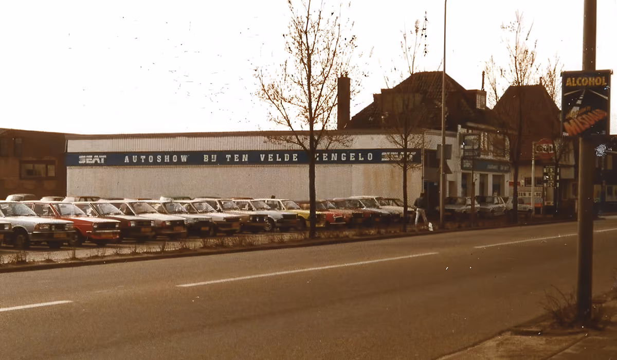 Historische foto van de autoshow bij Ten Velde in Hengelo met auto's op het voorterrein