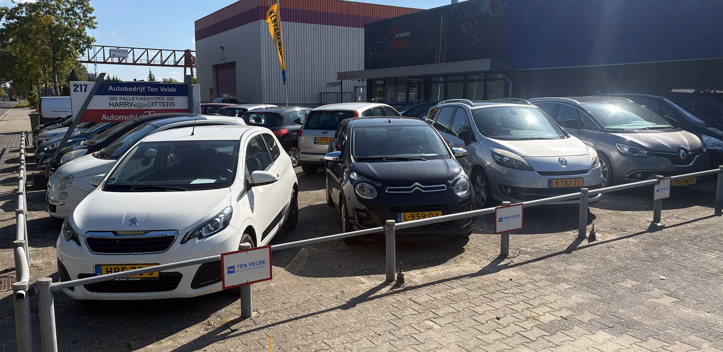 Buitenaanzicht van Autobedrijf Ten Velde in Enschede met occasions op het voorterrein.