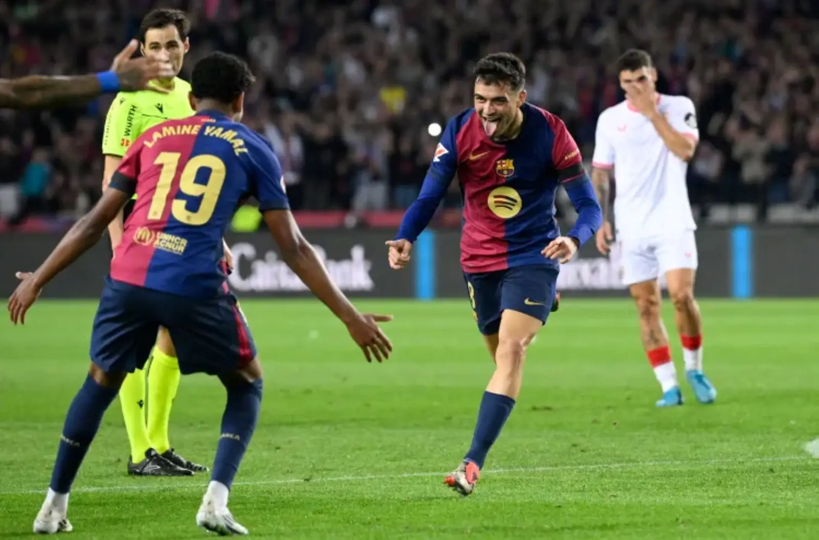 Pedri runs towards Lamine Yamal with his arms out after scoring against Sevilla, with a Sevilla defender walking away behind them