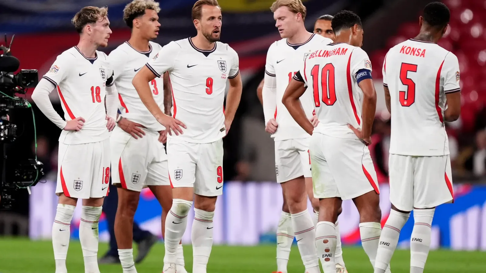England players, including Harry Kane, Jude Bellingham and Ezri Konsa, gather on the pitch before a match.