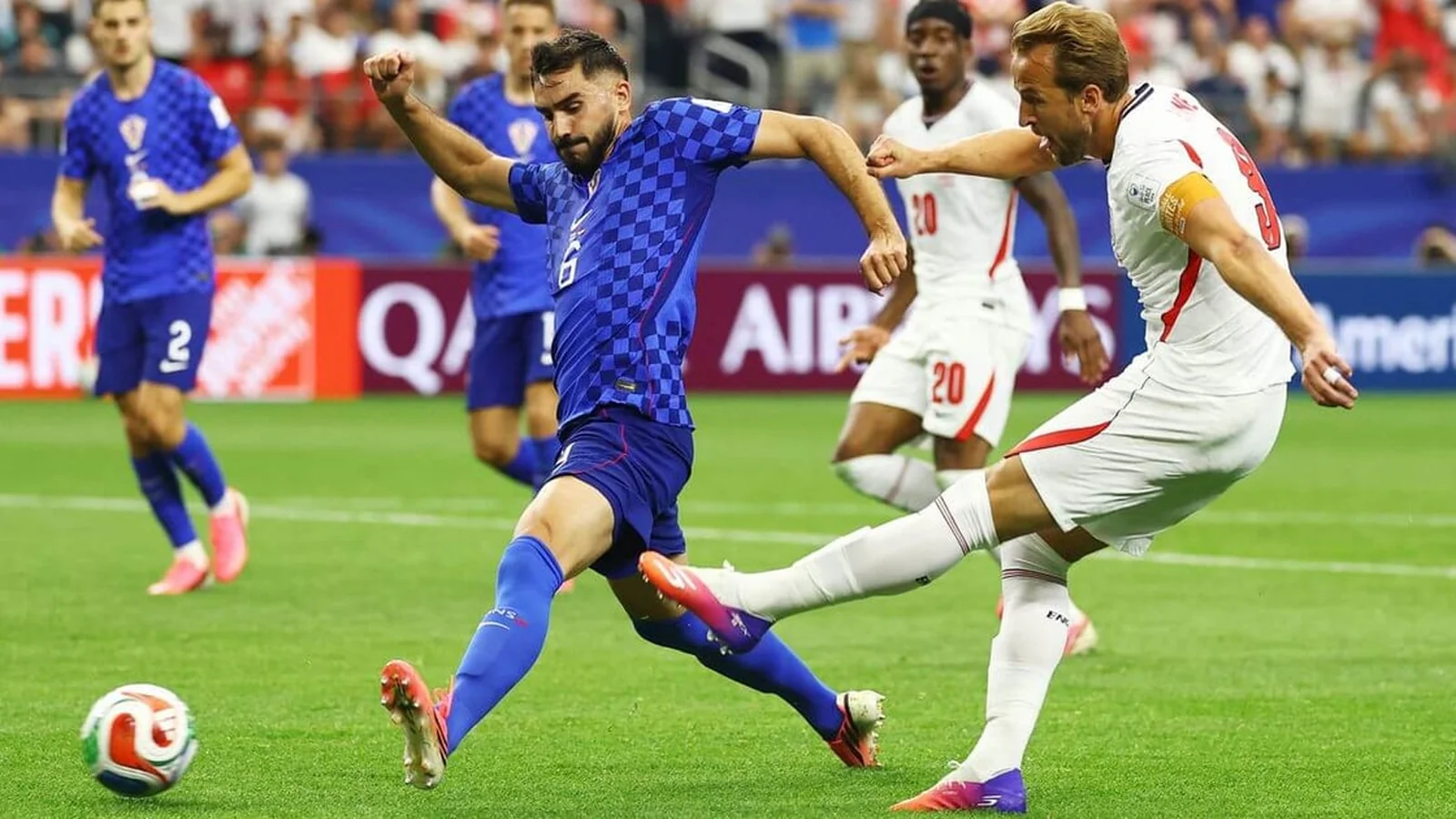 Harry Kane takes a shot for England while challenged by a Croatia defender during an international football match.