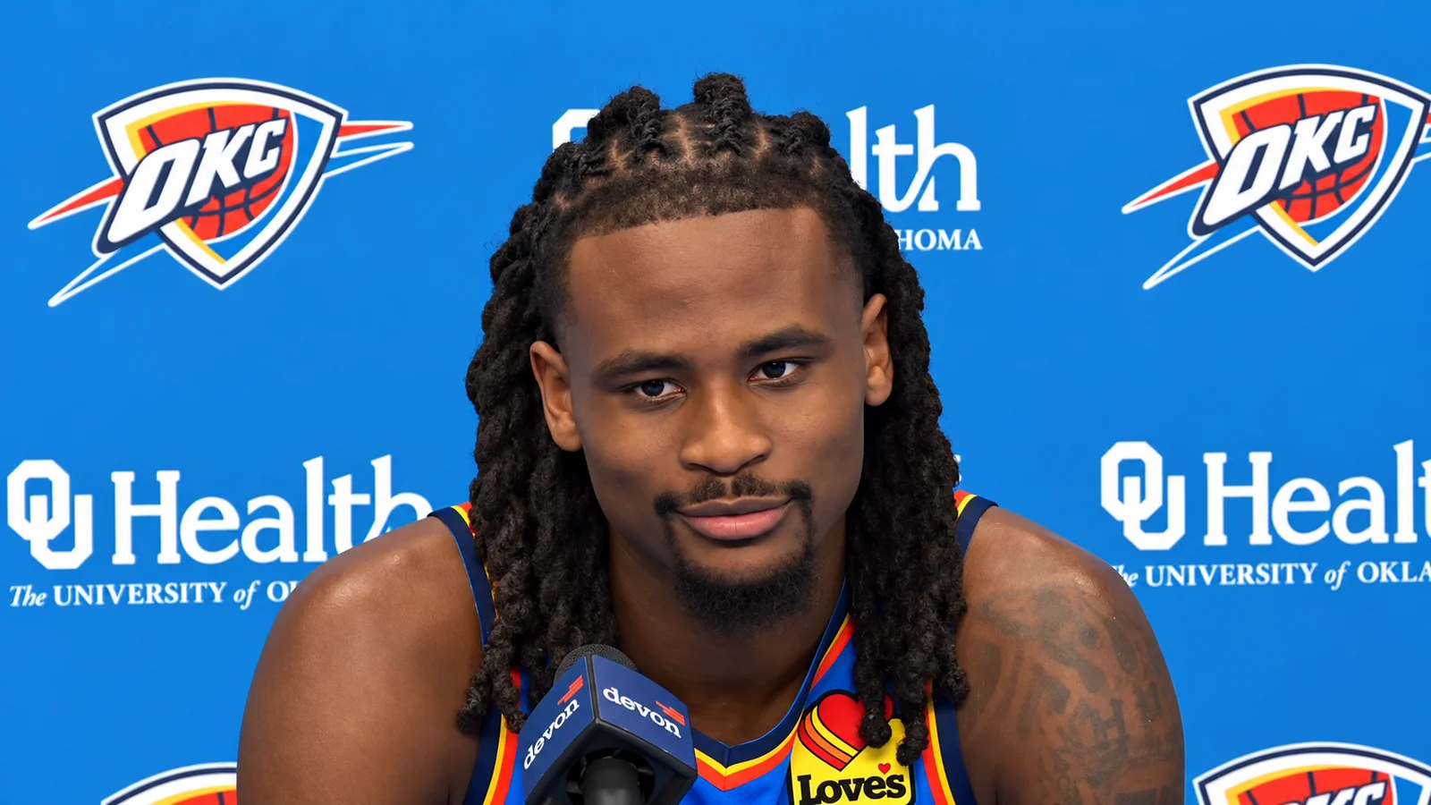 Oklahoma City Thunder player speaks at a press conference in front of an OKC and OU Health backdrop.