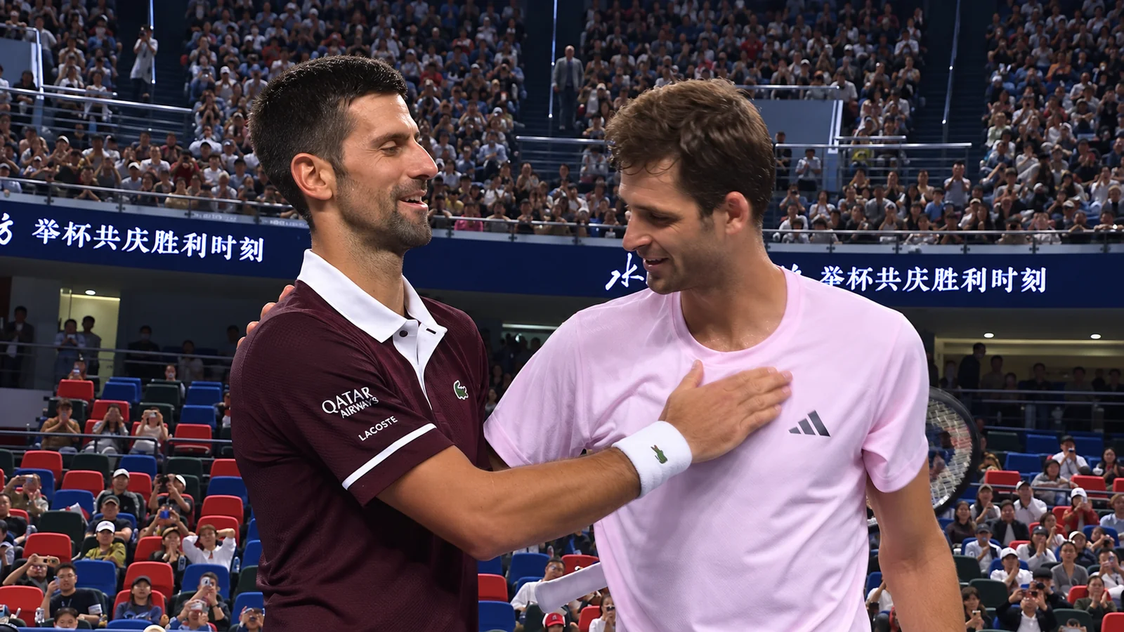 Two tennis players share a sportsmanlike moment after their match in front of a packed crowd at the Shanghai Masters.