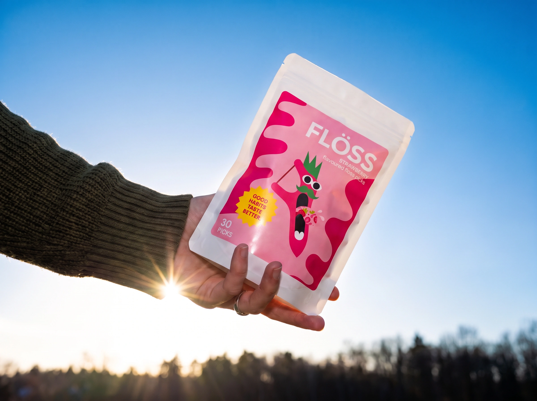 Person holding a pouch of FLOSS floss picks
