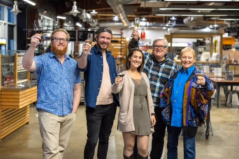 The editorial team of Unpretentious Palate—Justin Burke, Travis Mullis, Peter Taylor, and Anita Skogland—posing together in a casual, creative workspace.