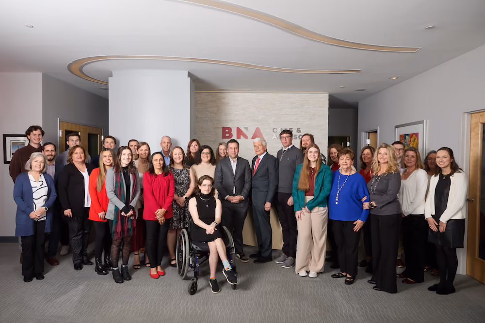 BNA Team: A group photo of the BNA team members smiling together at the 2024 holiday party, held at the BNA office in Riverwalk, showcasing the festive decorations.