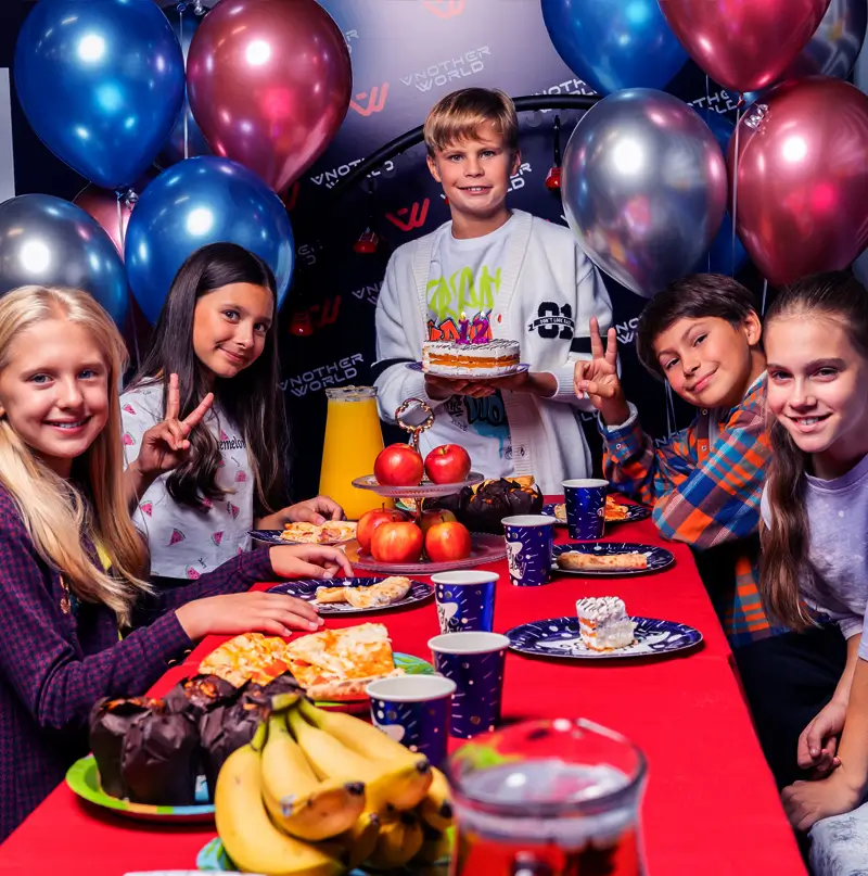 Children around a birthday table with balloons in the party lounge