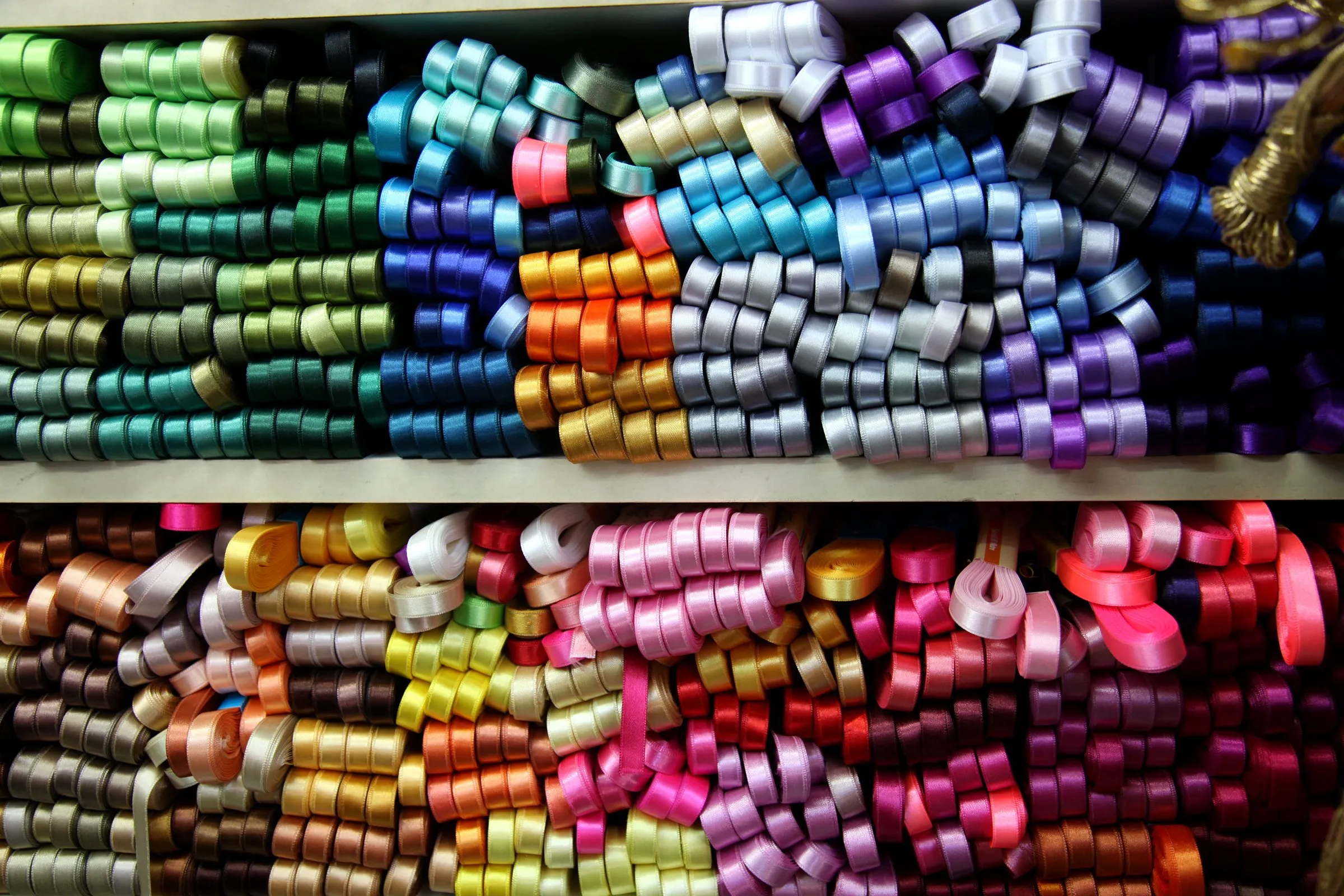 Regal mit aufgerollten Satinbändern in vielen Farben: Material für Labels und Details
