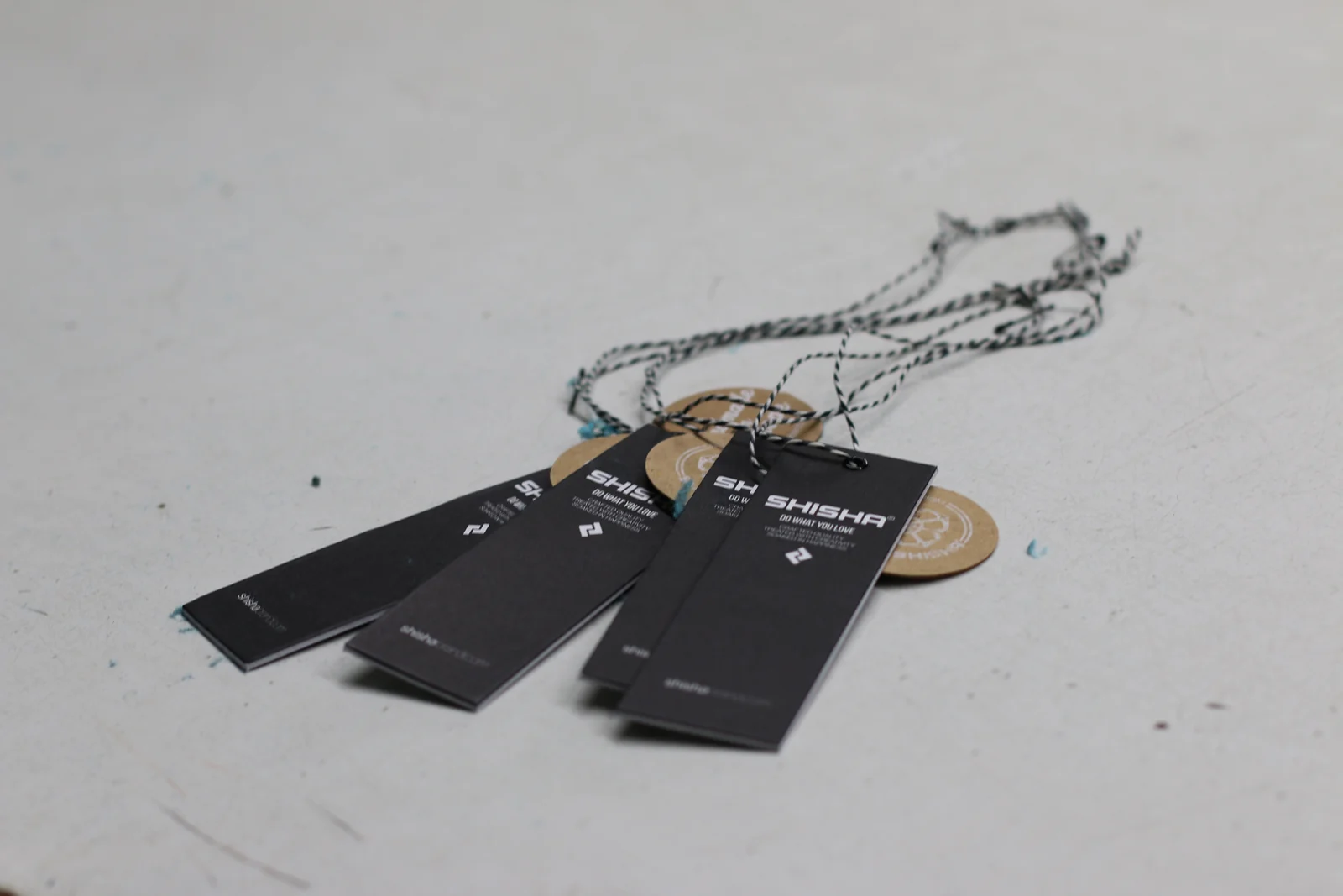 Schwarze und braune Hangtags mit Kordeln auf einem Arbeitstisch.
