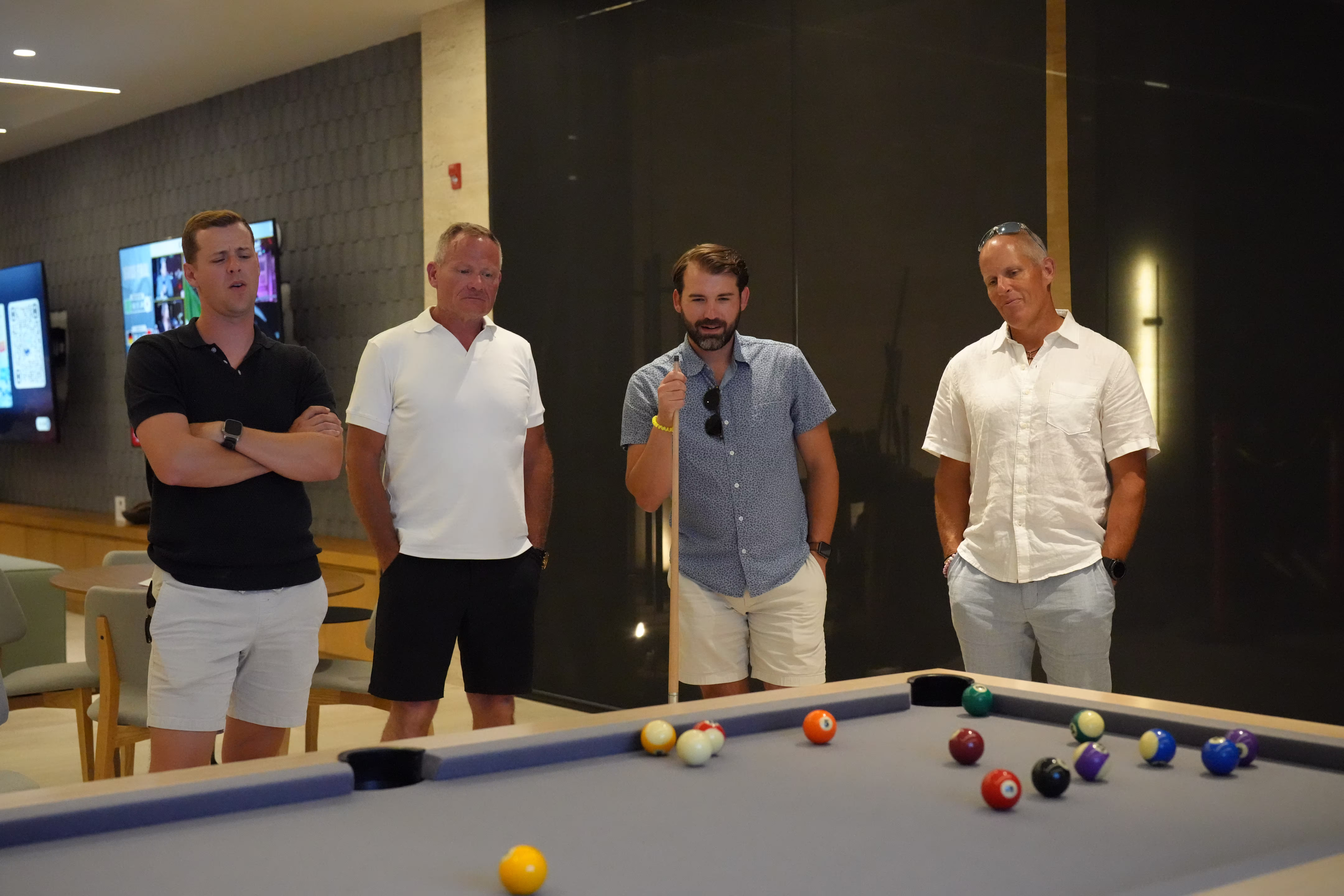 Person walking on a wooden suspension bridge surrounded by dense green forest.