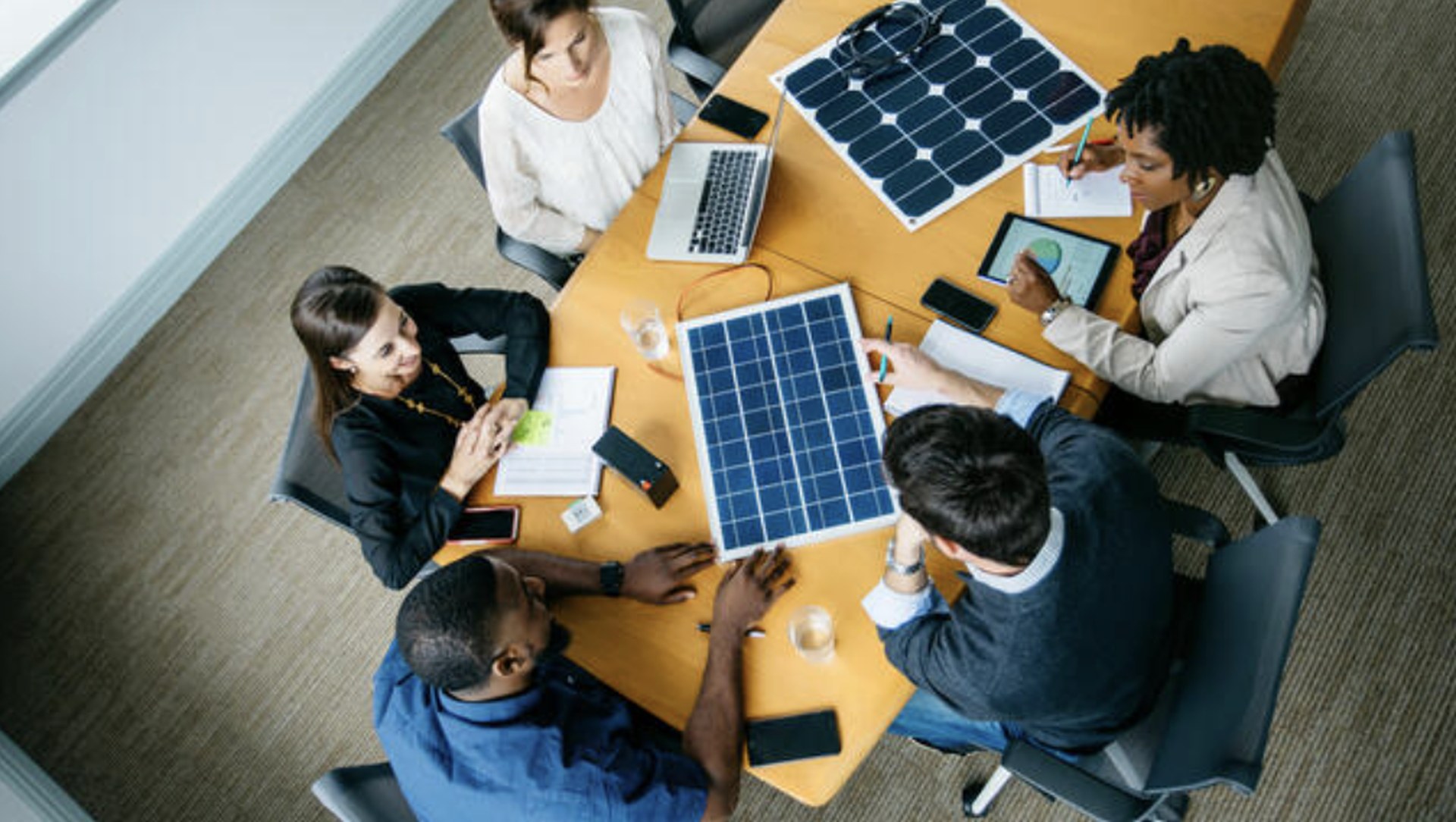 Sales team reviewing solar panels around a meeting table