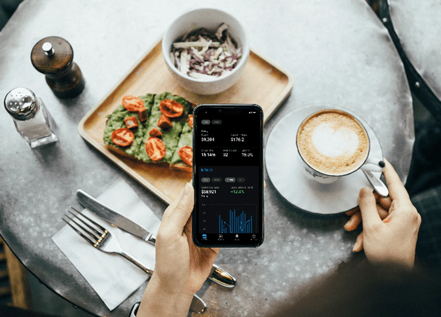 Live trading figures open on a phone beside breakfast on a cafe table