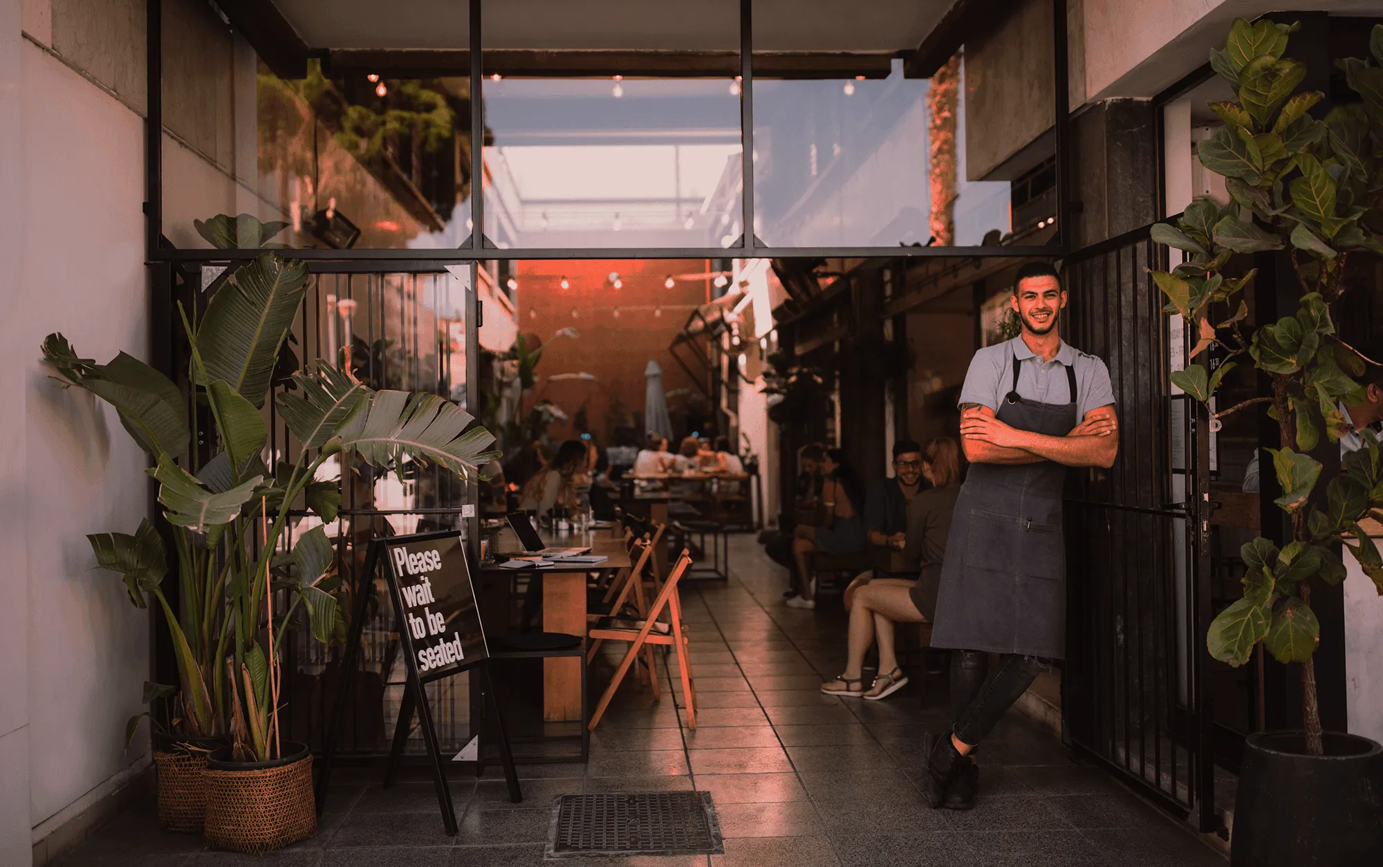 Owner standing in the doorway of his restaurant in the evening