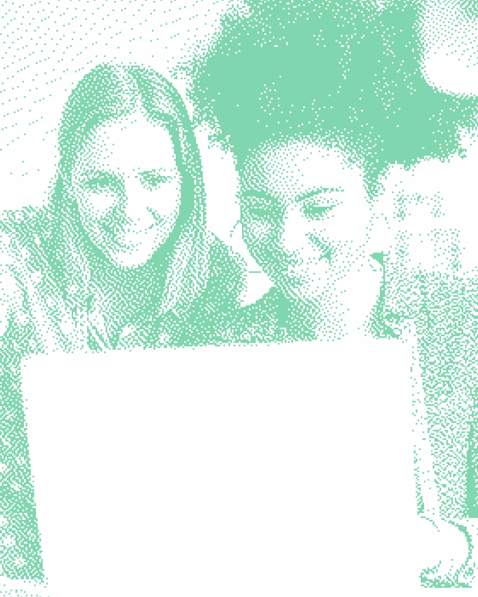 Two smiling people, one with long hair and the other with curly hair, looking at a laptop screen together.