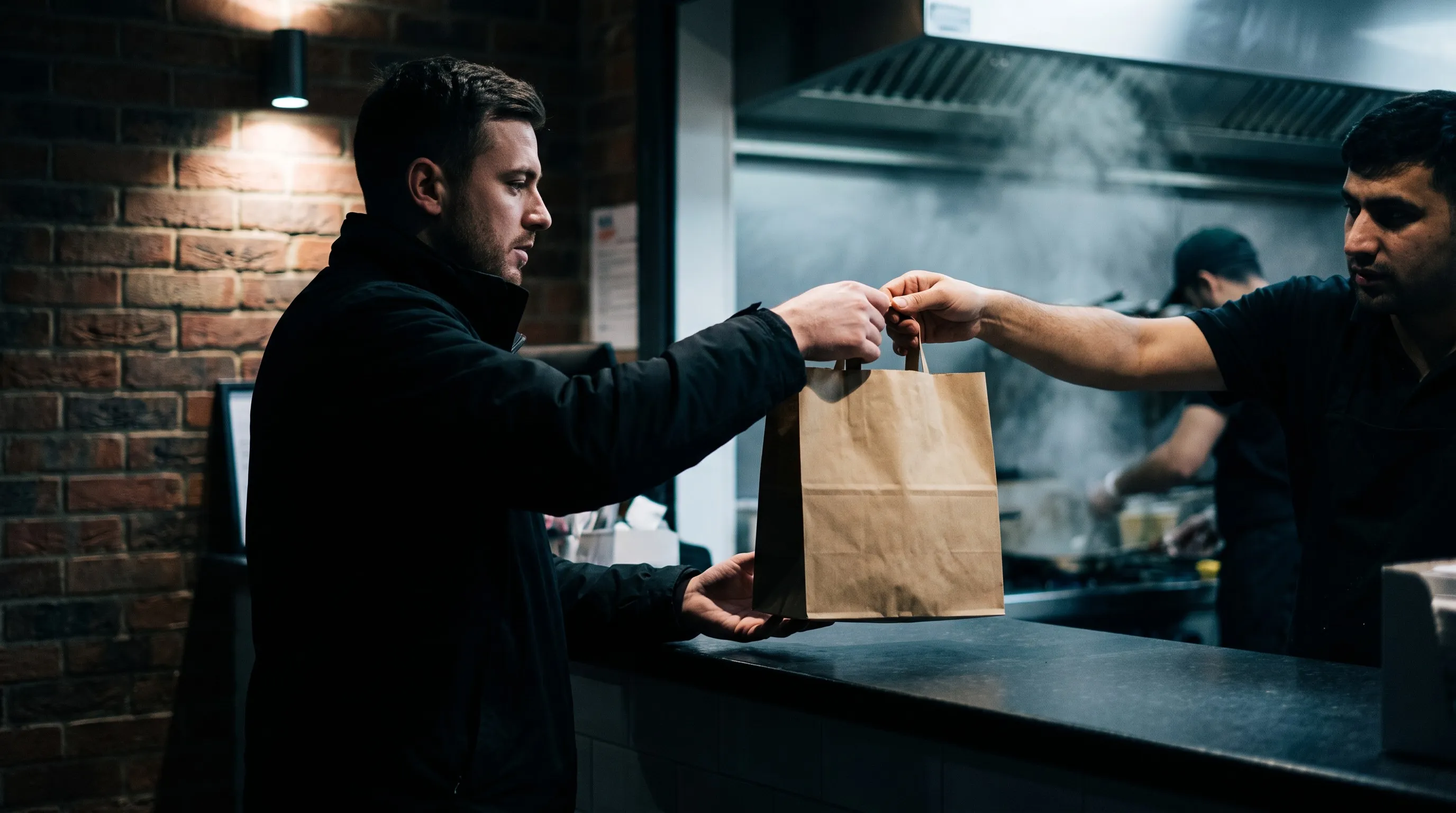 Takeaway order in a paper bag handed across the counter for collection
