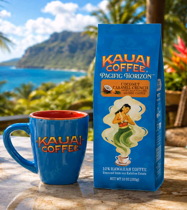 A bag of Kauai Coffee and a branded mug on a lanai overlooking the Hawaiian coast