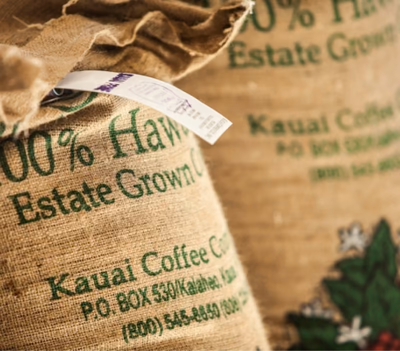 A burlap sack labelled 100% Hawaiian Estate Grown, Kauai Coffee Company