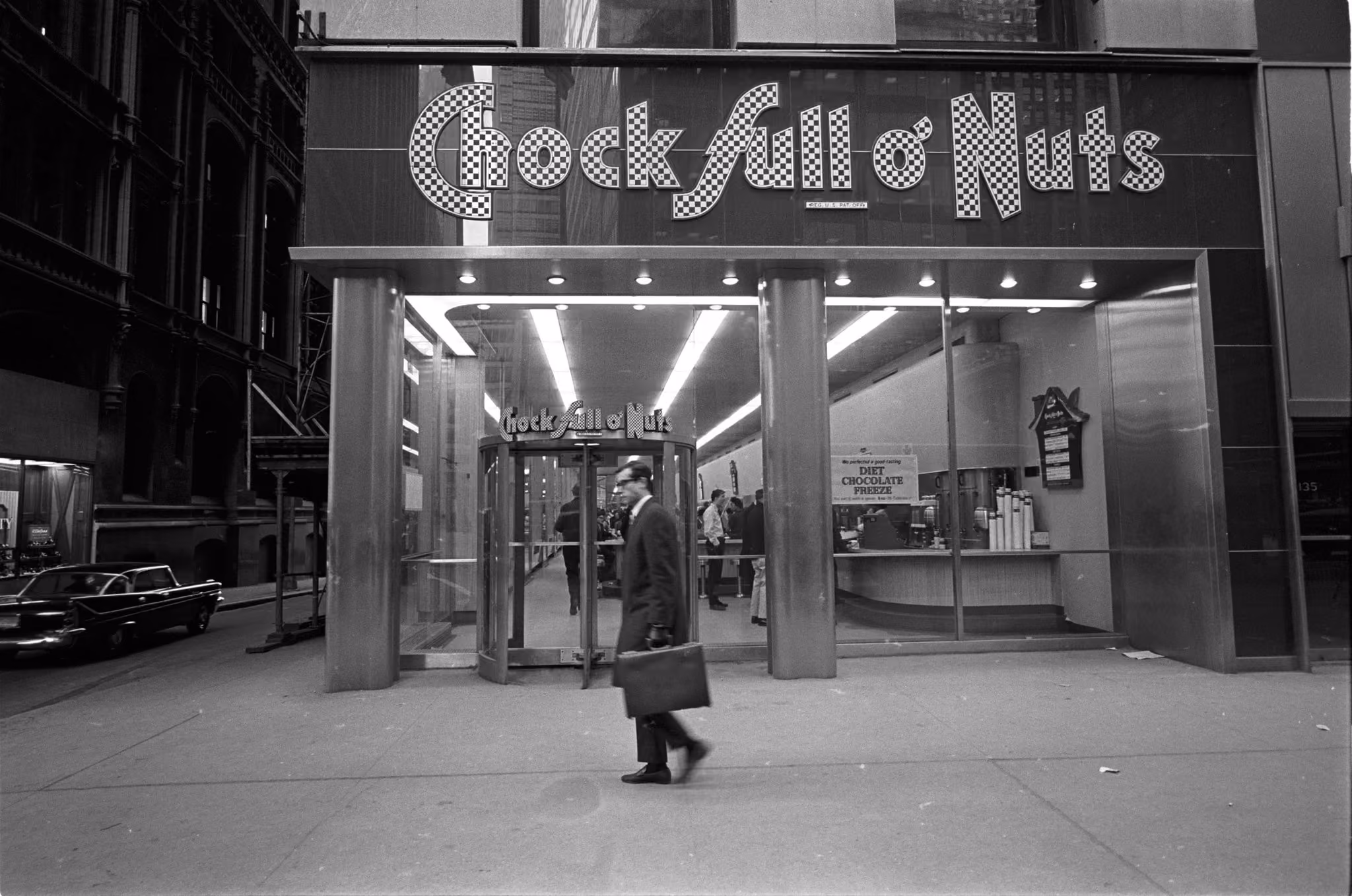 A person walking past the Chock full o'Nuts storefront on a New York street