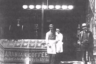 A vintage photograph of two men outside an early Hills Bros. Arabian Coffee storefront