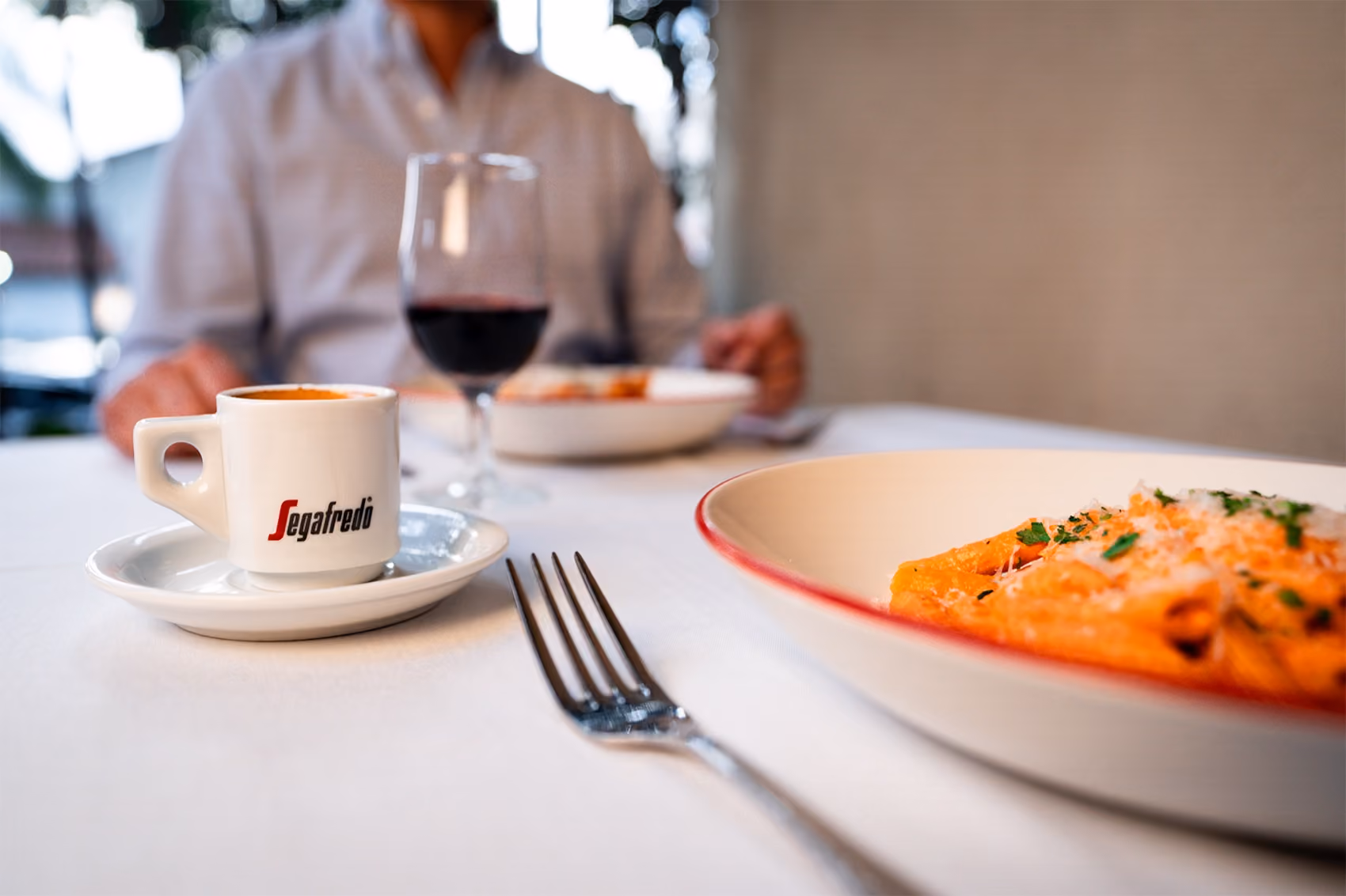 A Segafredo espresso served alongside a pasta dish at a restaurant table