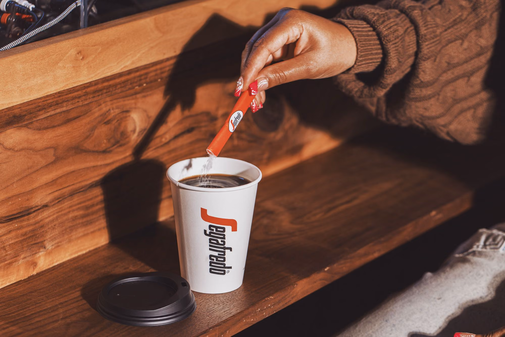 Pouring a sugar stick into a Segafredo paper cup