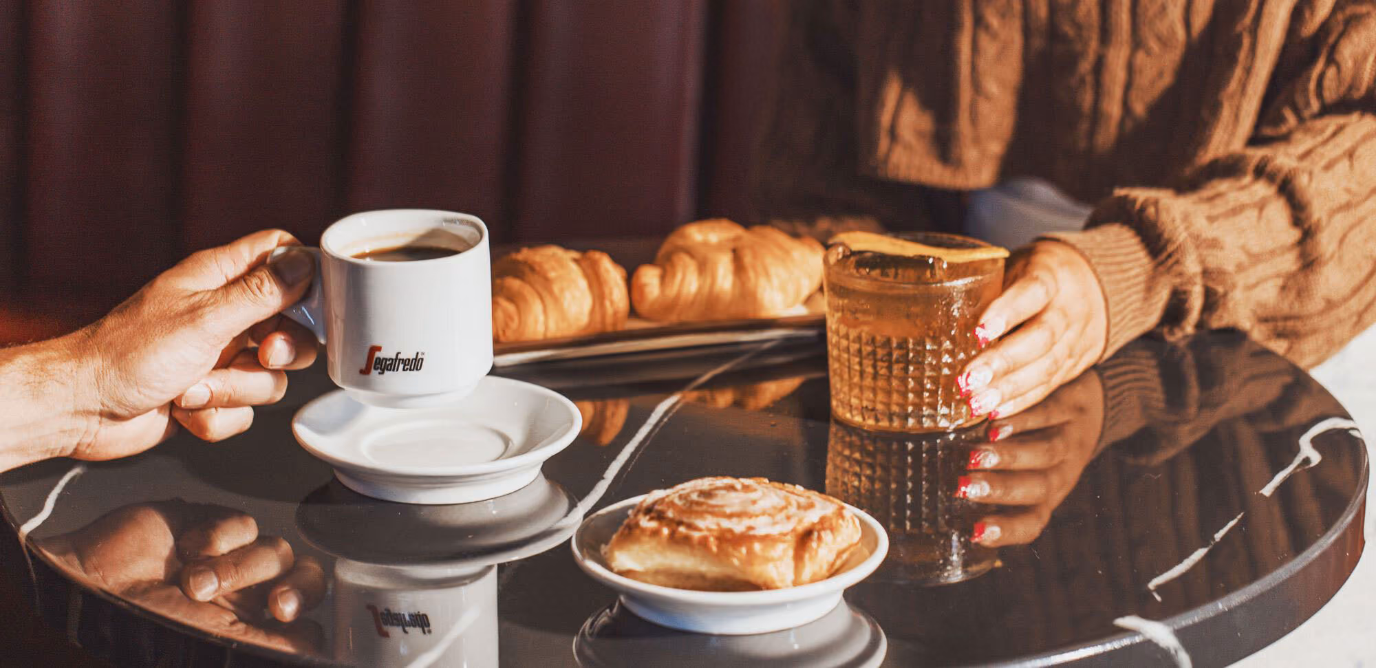 A barista steaming milk behind a Segafredo espresso bar