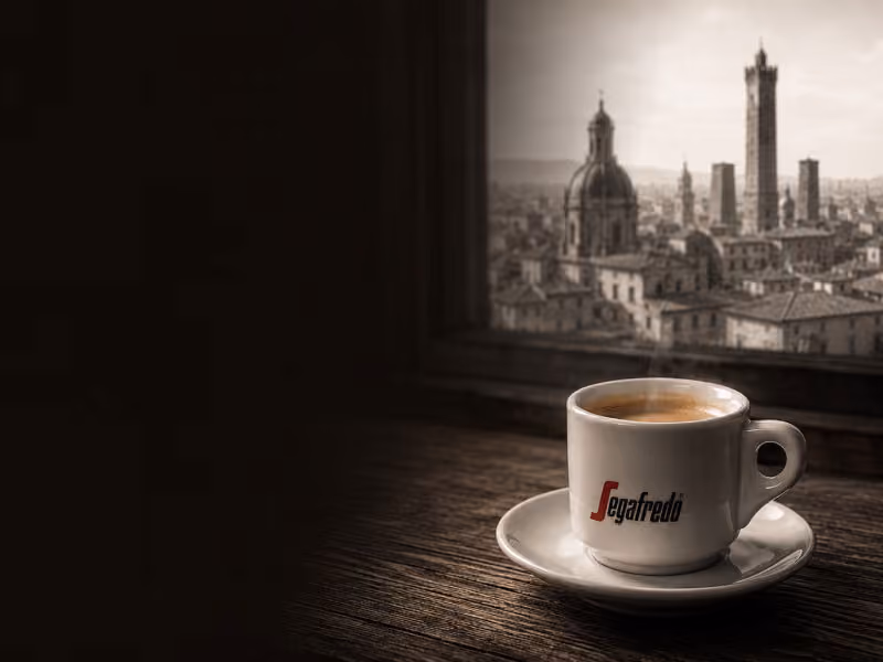 An espresso on a wooden windowsill overlooking the towers and rooftops of Bologna, Italy