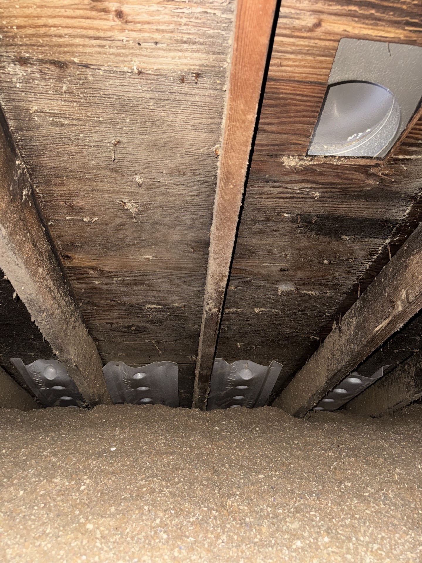Attic inspection showing existing roof decking, rafters, insulation, and ventilation baffles