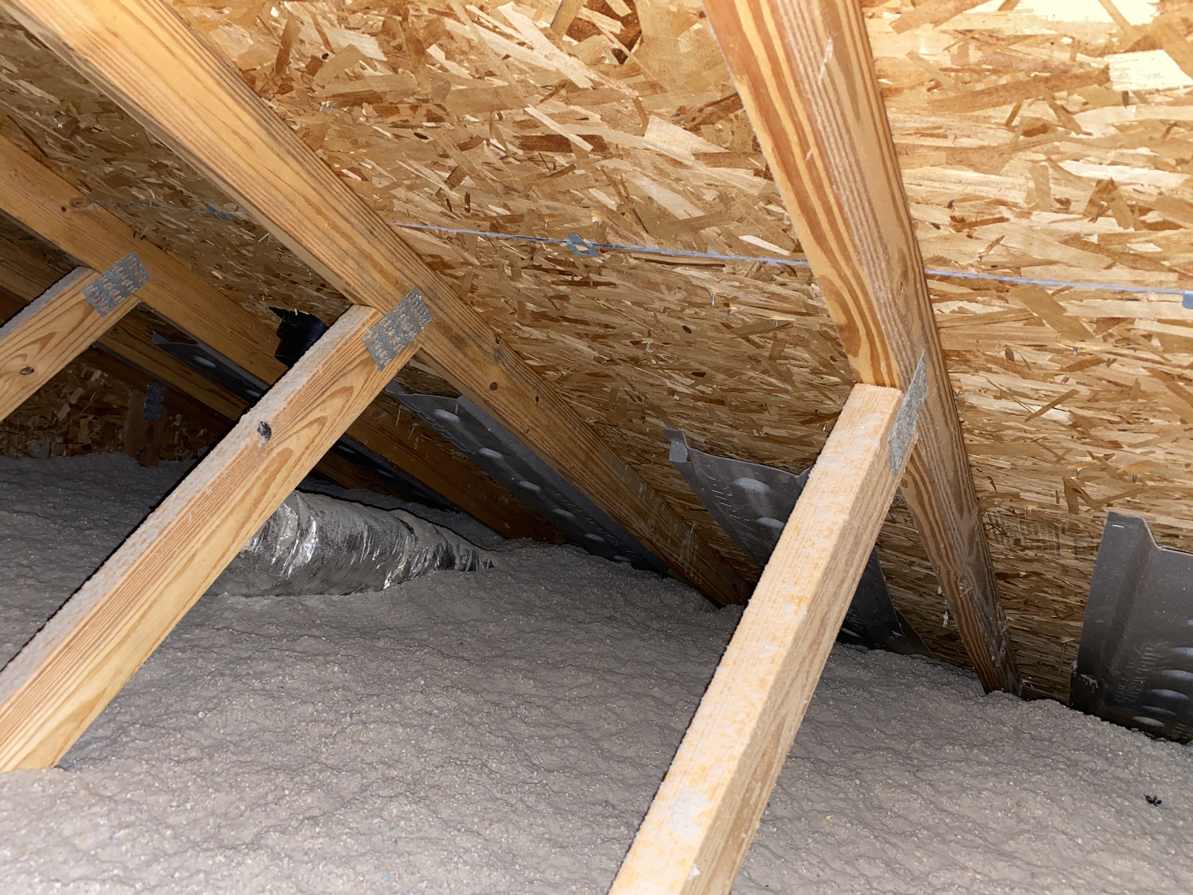 Armor Roofing attic inspection showing roof decking, trusses, insulation, and ventilation baffles