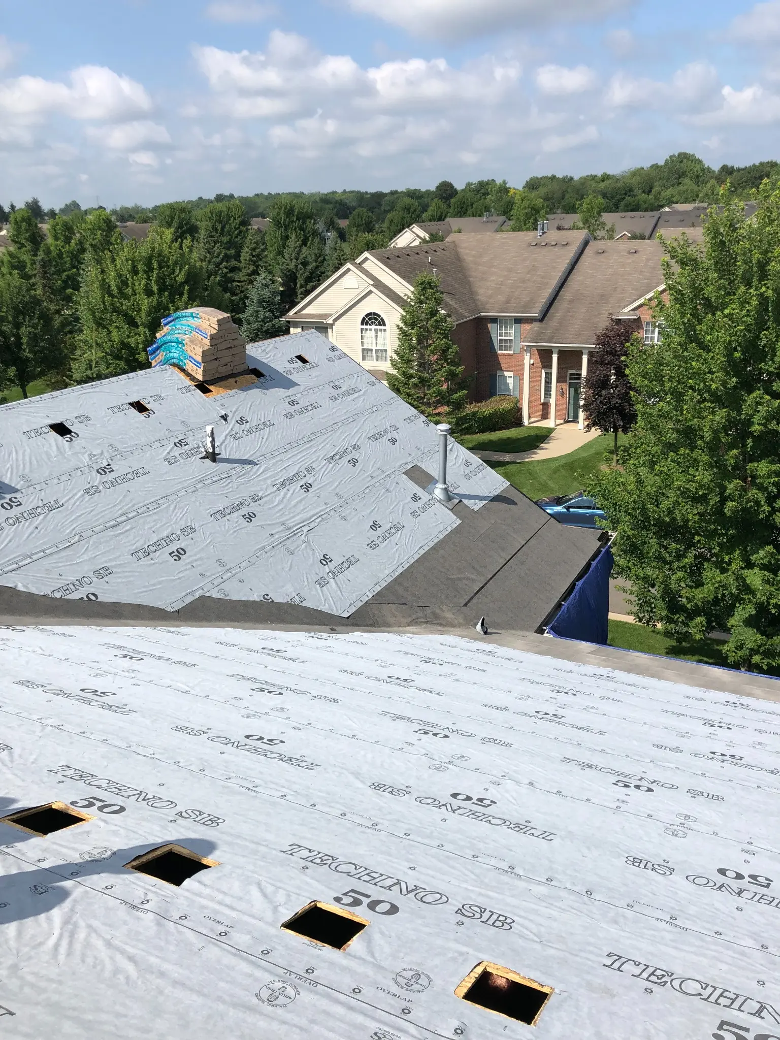 Roof replacement in progress with deck protection installed across the roof surface
