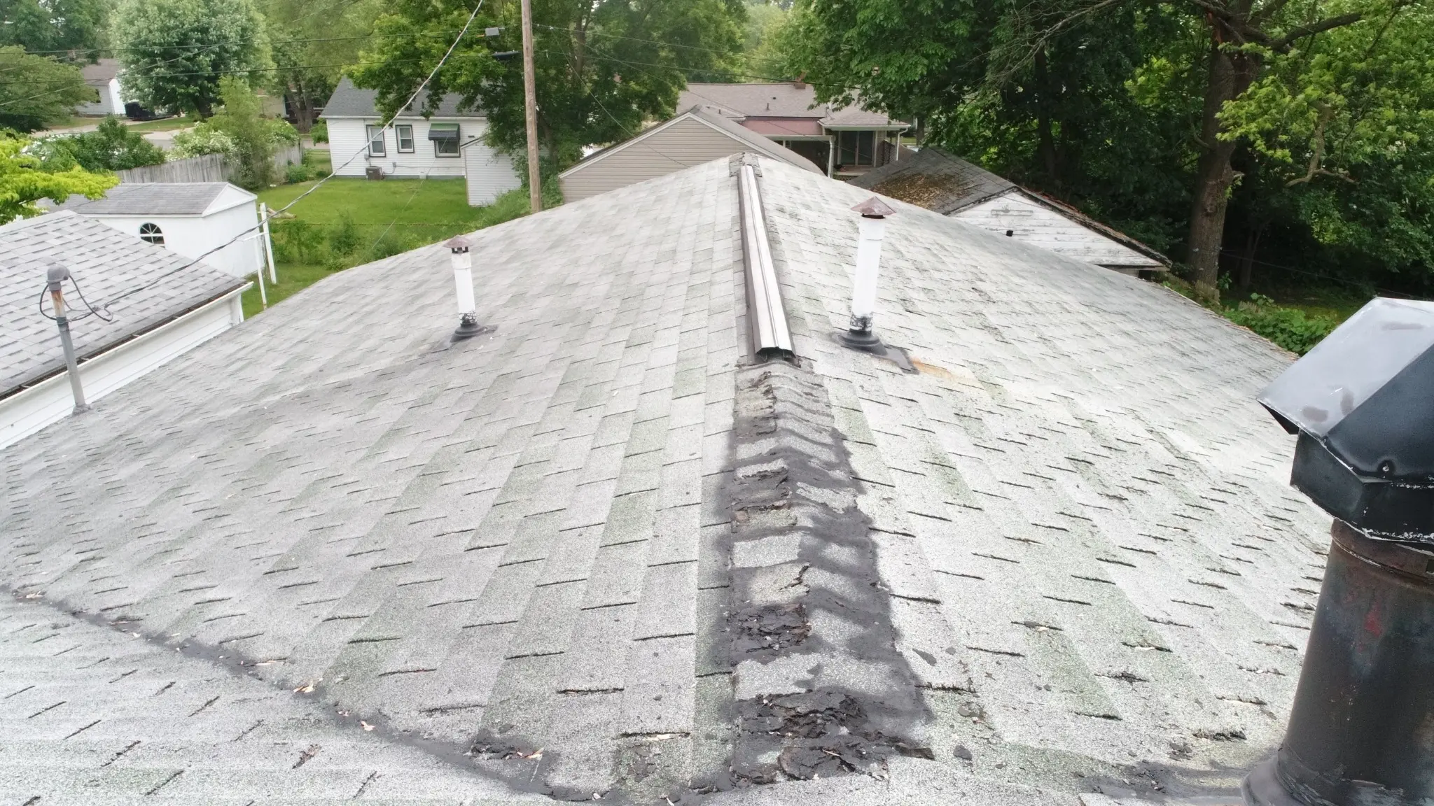Aged asphalt shingle roof with visible wear and deteriorated ridge conditions