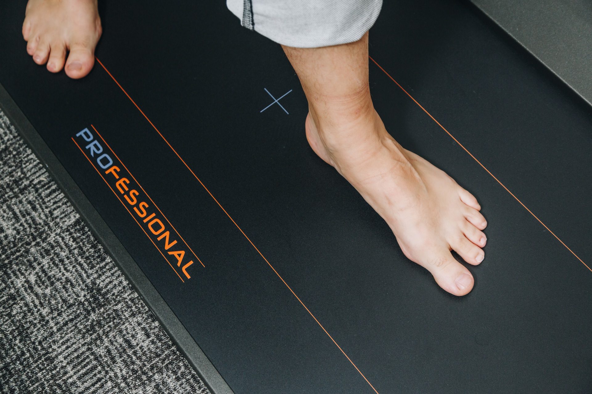 Patient standing on a pressure plate during podiatry gait and biomechanical assessment