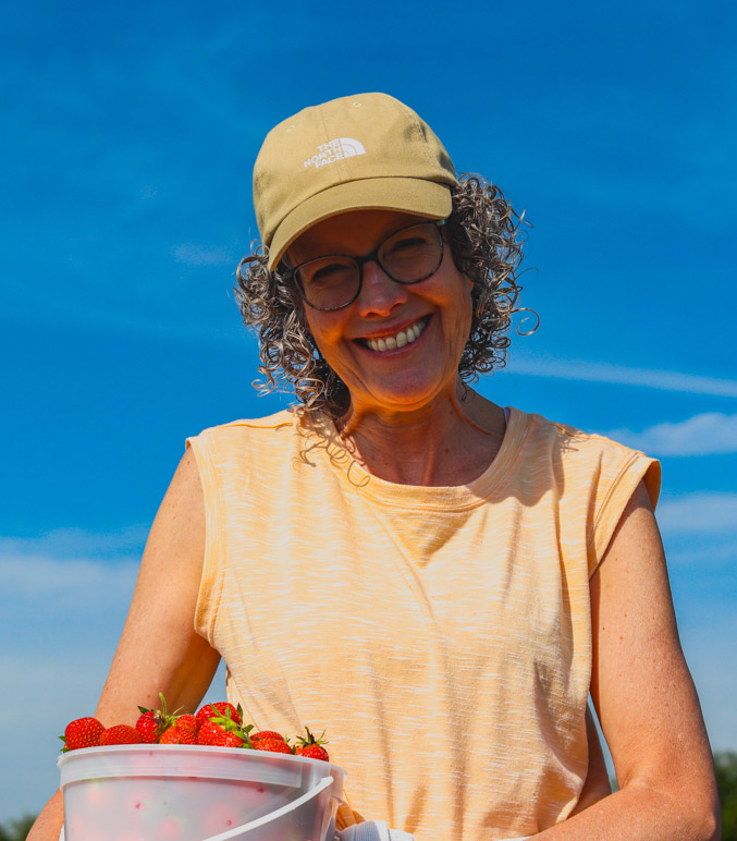 Angie Cormier holding a pail of strawberries in the field at Cormier's Berry Patch