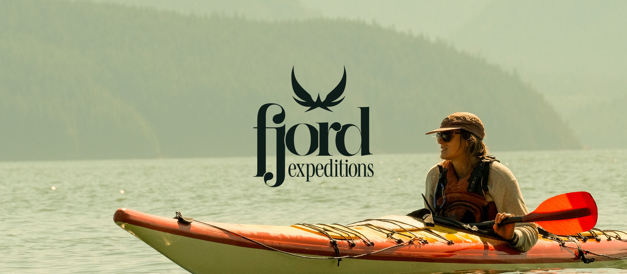 Fjord Expeditions logo over a sea kayaker paddling on calm coastal water