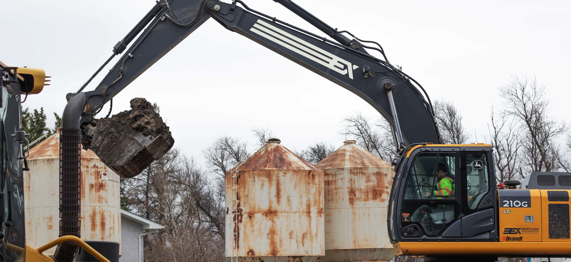 A Bestland Excavation excavator demolishing old grain bins on a Manitoba farm