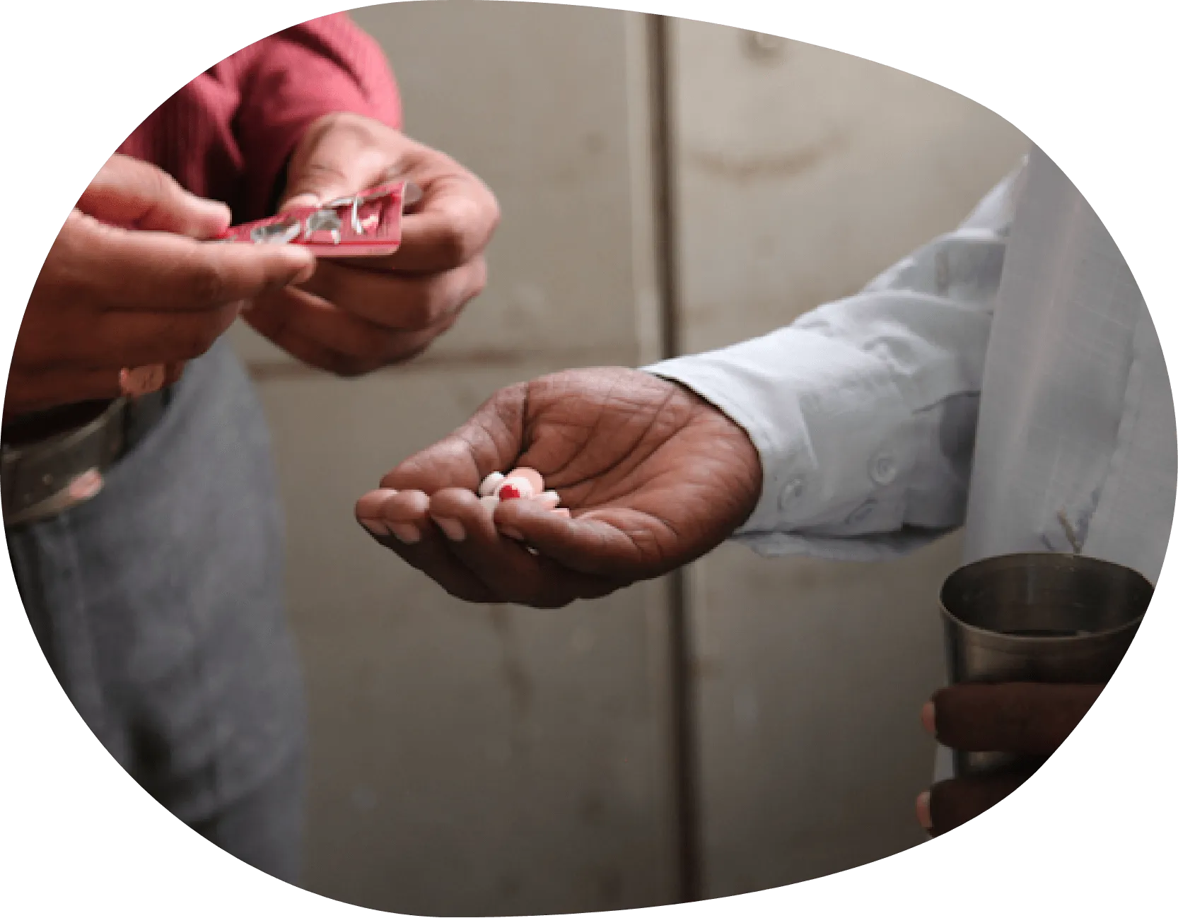 One man giving pills to another man who is the holding pills in his right hand.