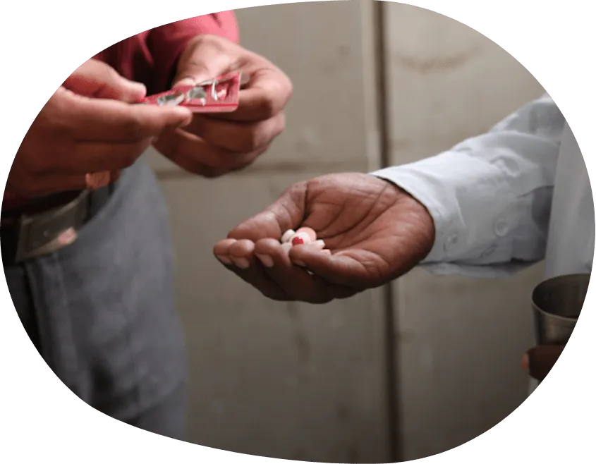 Man giving pills to another man who is holding pills in his right hand.