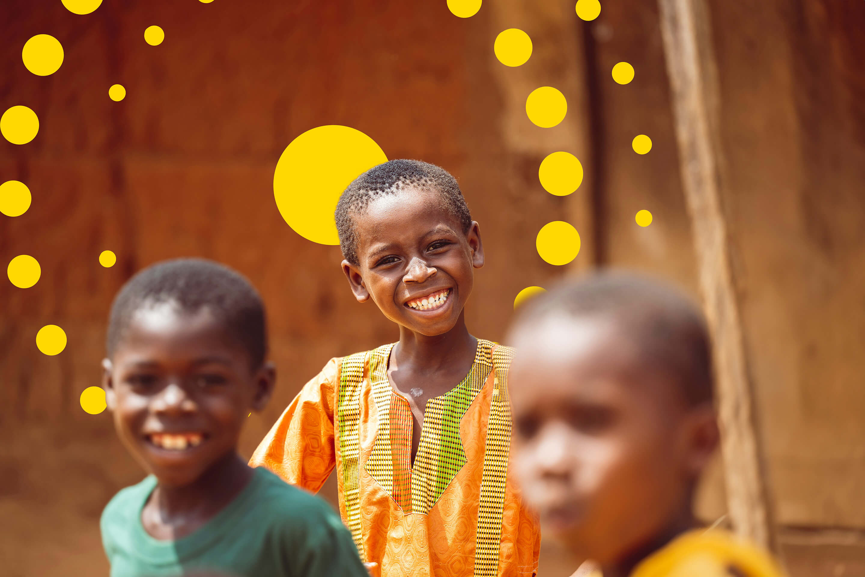 Children smiling outside a village building